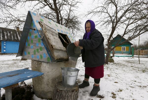 Женщина набирает воду из колодца в Белоруссии