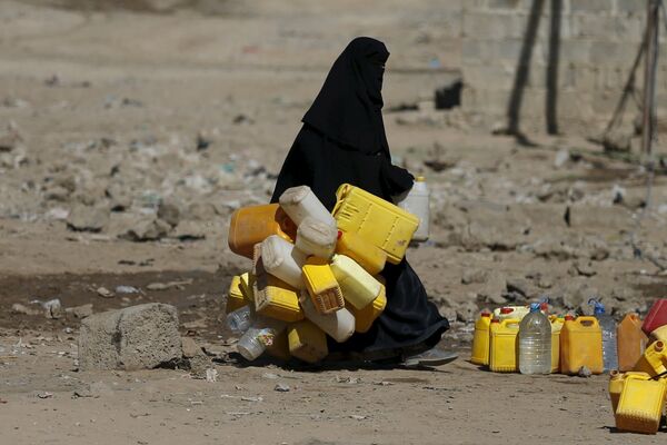 Женщина с канистрами идет за питьевой водой в городе Сана, Йемен