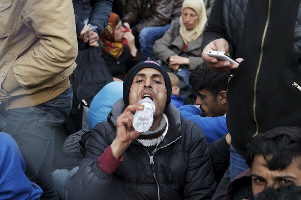 Мигрант пьет воду во время ожидания на греко-македонской границе