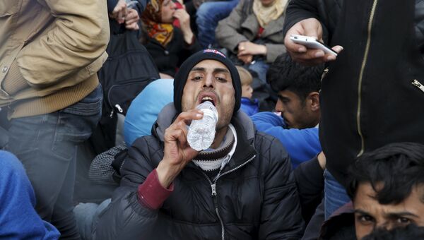 Мигрант пьет воду во время ожидания на греко-македонской границе