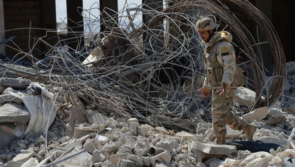 Боец отряда народного ополчения Соколы пустыни у разбитого здания в результате боев в 10-ти км к западу от Пальмиры