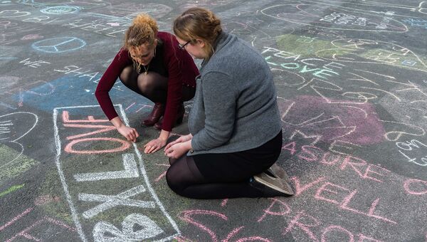 Люди рисуют мелом в память о жертвах терактов в Брюсселе возле Брюссельской фондовой биржи
