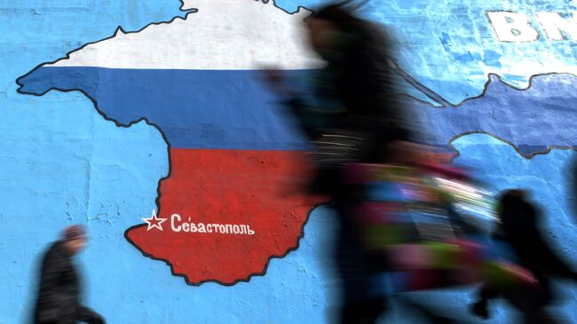 Прохожие у нарисованной на стене карты Крыма в цветах российского флага. Архивное фото