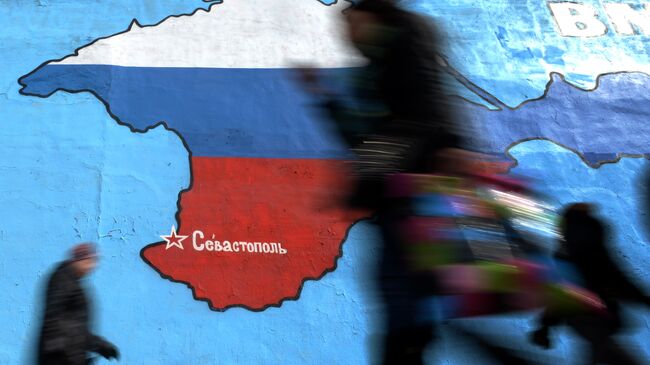 Прохожие у нарисованной на стене карты Крыма в цветах российского флага в Москве. Архивное фото
