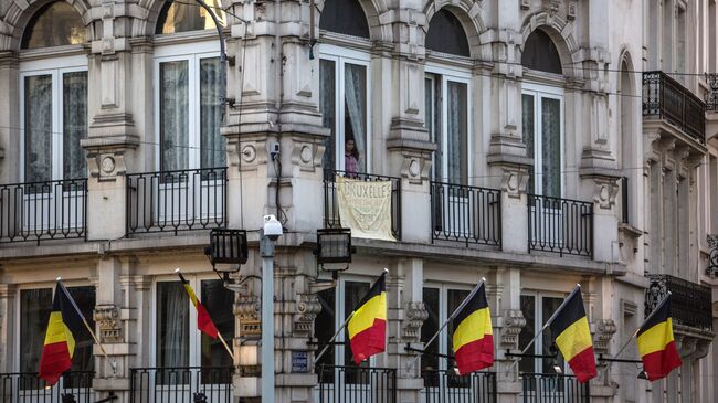 Мужчина в окне здания на Биржевой площади в Брюсселе