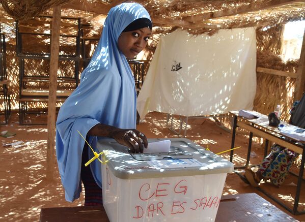 Женщина бросает бюллетень во время президентских выборов на избирательном участке в Ниамей, Нигера