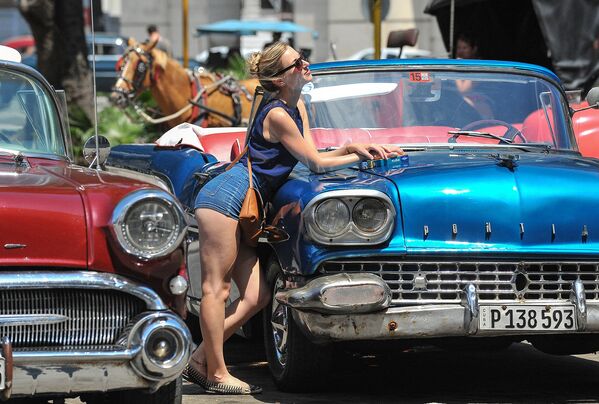 Турист фотографируется с ретро-автомобилей в Гаване
