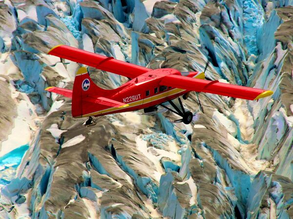 Самолет пролетает над горными ледниками Аляски