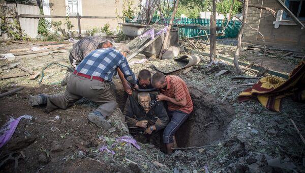 Местные жители достают из укрытия тело погибшего в результате обстрела поселка Александровка в Донецкой области