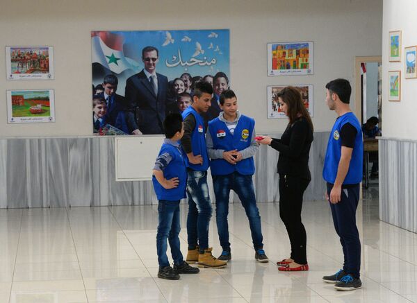 Представительница российской общественной организации Боевое братство разговаривает с учащимися во время посещения дамасской школы, где учатся дети погибших военнослужащих сирийской армии