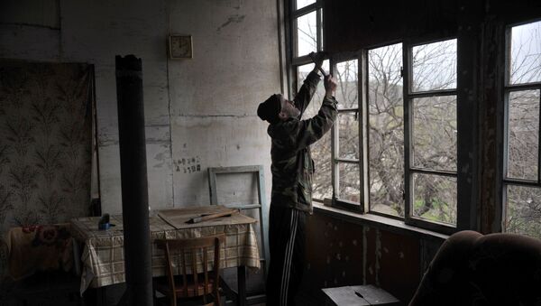 Местный житель заколачивает фанерой окна, выбитые артиллерийским взрывом в городе Мартакерт в Нагорном Карабахе. Архивное фото
