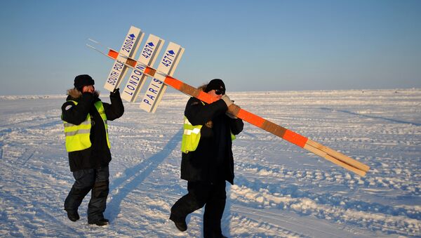 Сотрудники дрейфующей ледовой базы Барнео, находящейся в Арктике, несут символический столб, обозначающий Северный полюс. Архивное фото