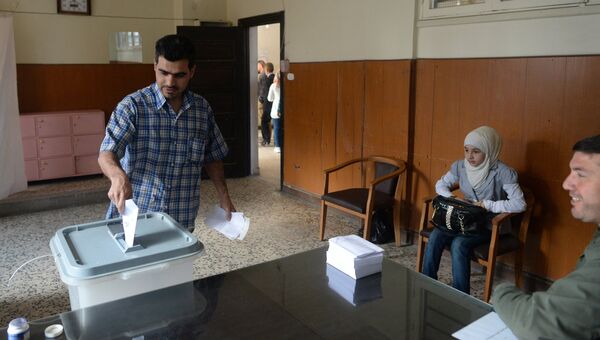 Мужчина опускает конверт с бюллетенем в урну на одном из избирательных участков во время голосования на парламентских выборов в Сирии. Архивное фото