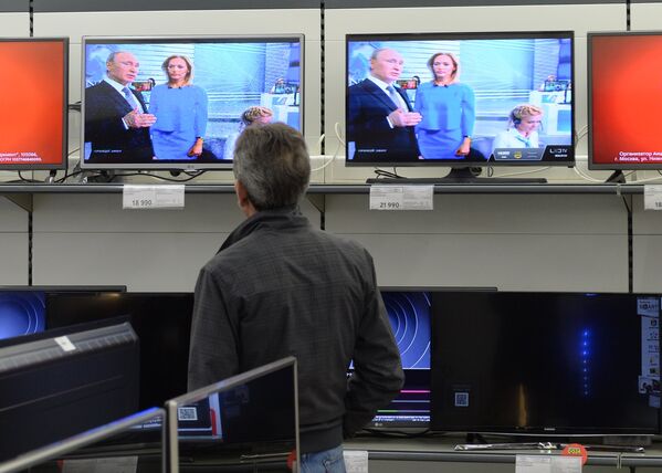 Посетитель магазина М-видео смотрит трансляцию ежегодной специальной программы Прямая линия с Владимиром Путиным