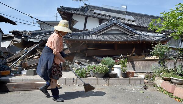 Женщина у своего разрушенного в результате землетрясения дома. Кумамото, Япония. Апрель 2016