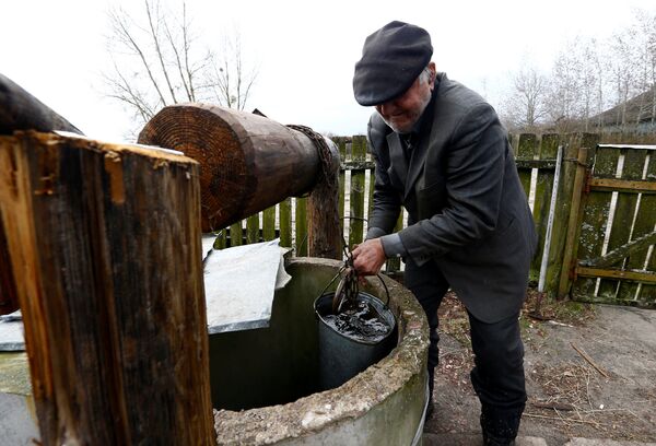 Житель зоны отчуждения Чернобыльской АЭС набирает воду из колодца