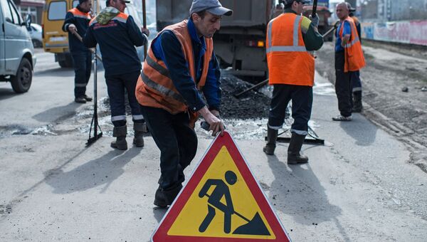 Рабочий устанавливает знак Дорожные работы на улице Кирова в Омске, где проходит ремонт дорожного покрытия