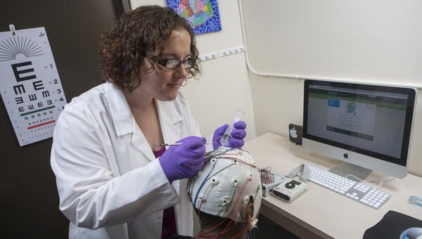 Ученые устанавливают электроды ЭЭГ на голову добровольца