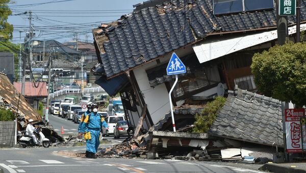 Полицейский среди разрушенных в результате землетрясения зданий в Кумамото, Япония