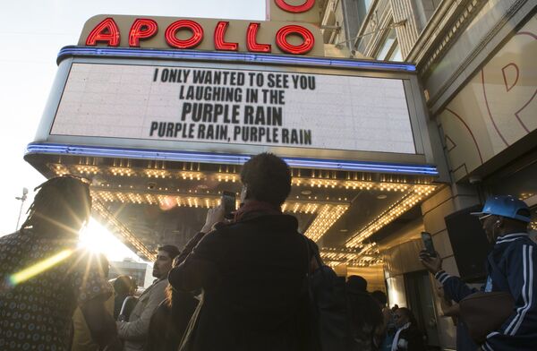 Люди слушают музыку Принса у театра Apollo в Нью-Йорке