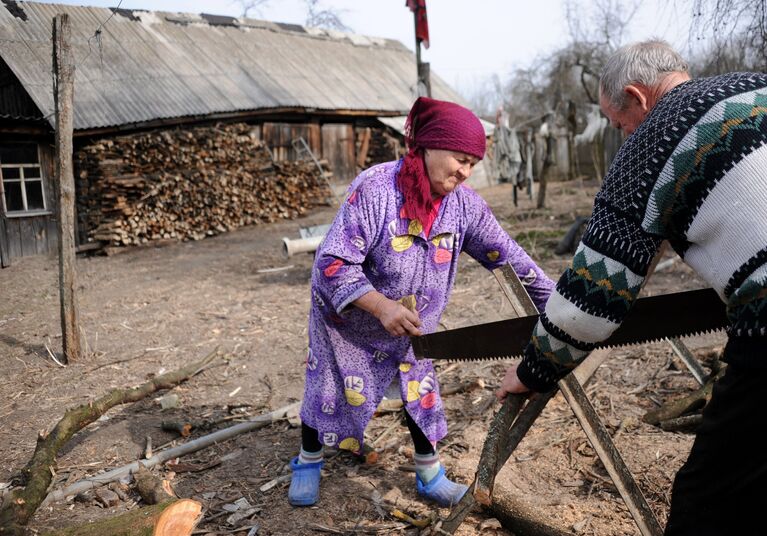 Валентина Бережняцкая (75 лет) и Иван Селуйко (78 лет) пилят дрова в деревне Савичи на территории Полесского радиационно-экологического заповедника в Белоруссии