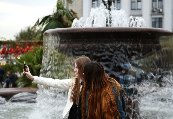 Девушки фотографируются у фонтана на Театральной площади в Москве