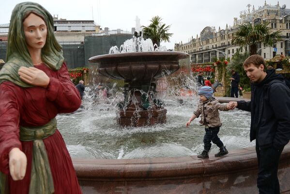 Мужчина с ребенком у фонтана на Театральной площади в Москве.