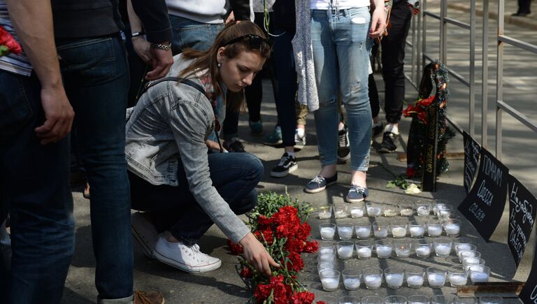 Девушка возлагает цветы во время акции в память о погибших при пожаре в одесском Доме профсоюзов у посольства Украины в Москве