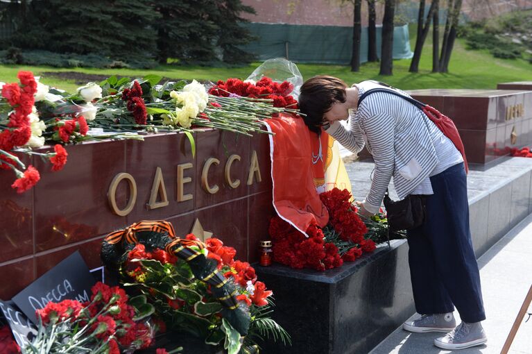 Женщина возлагает цветы к тумбе города Одессы у мемориала Могила Неизвестного Солдата в Александровском саду в Москве