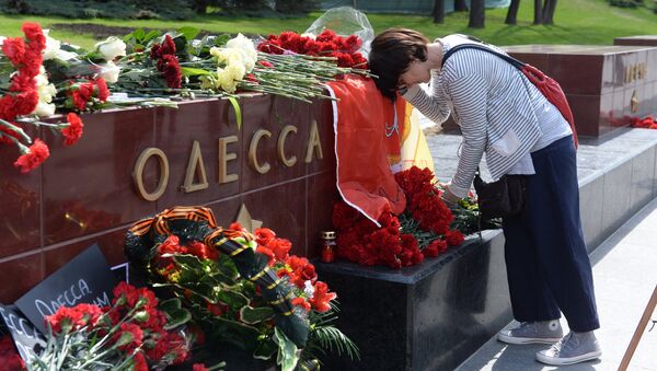 Женщина возлагает цветы к тумбе города Одессы у мемориала Могила Неизвестного Солдата в Александровском саду в Москве