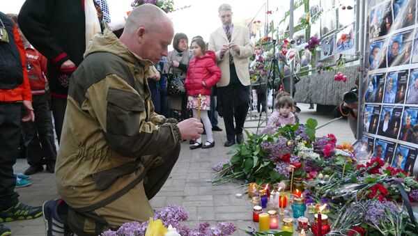 Мужчина зажигает свечу у Стенда памяти на площади имени Ленина в Донецке во время митинга в память о погибших при пожаре в одесском Доме профсоюзов