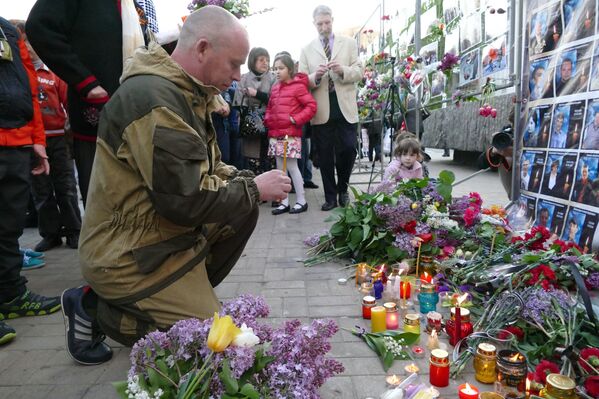 Мужчина зажигает свечу у Стенда памяти на площади имени Ленина в Донецке во время митинга в память о погибших при пожаре в одесском Доме профсоюзов