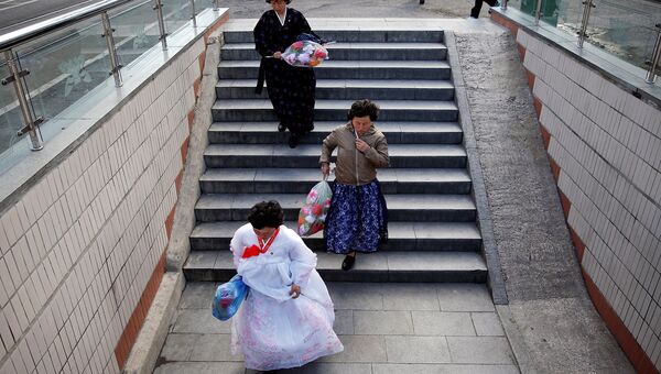 Женщины в традиционных костюмах спускаются в подземный переход в центре Пхеньяна, Северная Корея 4 мая 2016 года