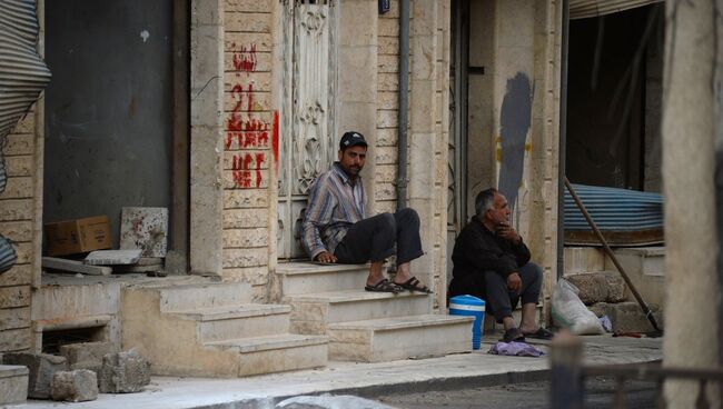 Мужчины сидят на крыльце дома на одной из улиц Пальмиры