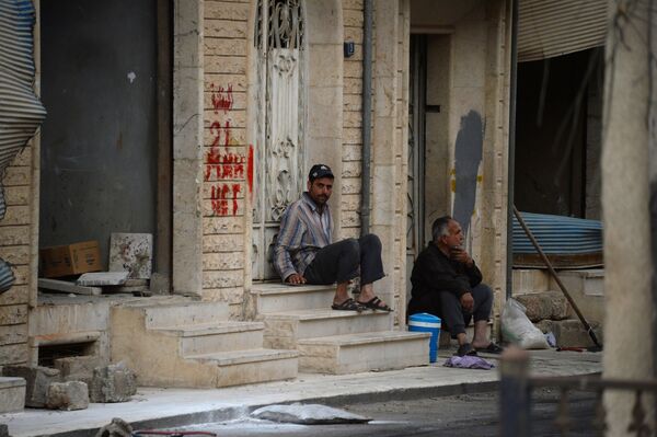 Мужчины сидят на крыльце дома на одной из улиц Пальмиры
