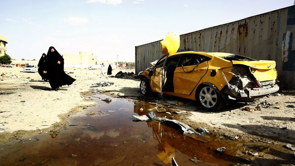 Иракские женщины проходят мимо поврежденного автомобиля в городе Эс-Самава, Ирак. Архивное фото