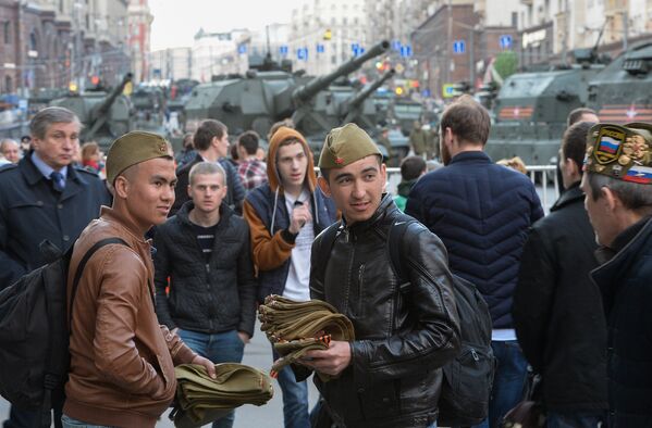 Продавцы пилоток на Тверской улице в Москве, где проходит военная техника для репетиции военного парада на Красной площади