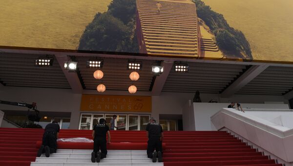 Рабочие укладывают красную ковровую дорожку у кинотеатра на набережной Круазет перед открытием 69-го Каннского кинофестиваля
