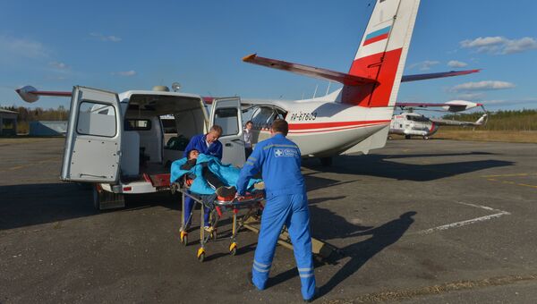 Сотрудники выездной экстренной консультативной бригады скорой медицинской помощи помещают пациента в самолет L-410 в аэропорту Вельска для отправки в Архангельск