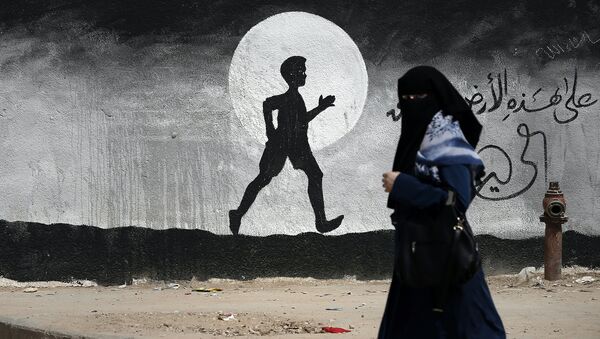Жительница проходит мимо граффити на стене школы ООН в секторе Газа, Палестина