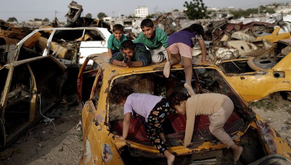 Палестинские дети играют среди разбитых автомобилей в секторе Газа. Архивное фото