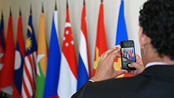 Участник саммита Россия — АСЕАН фотографирует флаги в конгресс-центре в Сочи