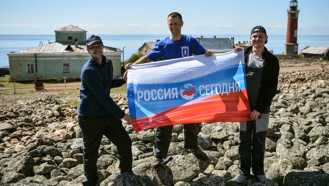 Журналисты МИА Россия сегодня Владимир Лебедев, Андрей Кирсанов и Евгений Еремкин с флагом агентства во время комплексной экологической экспедиции Русского географического общества Гогланд на острове Гогланд