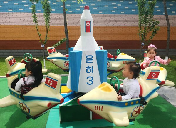Дети катаются на карусели в виде северокорейского спутника Ынха-3 (Млечный путь-3) в одном из детских садов Пхеньяна