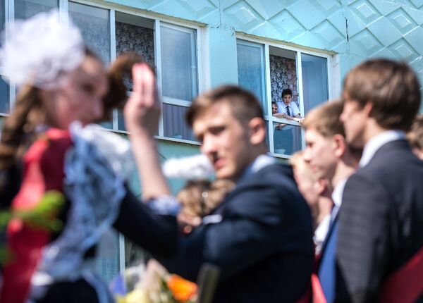 Школьники наблюдают за выпускниками во время праздника Последний звонок в гимназии №1 им. А.Лупова в городе Тара Омской области