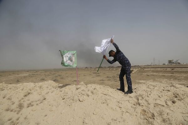 Полицейский ставит флаг иракской федеральной полиции рядом с флагом шиитского ополчения