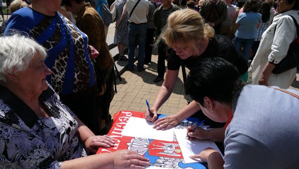 Жительница Донецка во время митинга подписывает петицию против нарушения Киевом резолюции Совета безопасности ООН