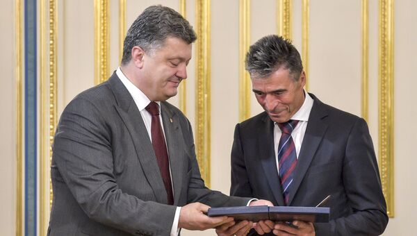 Президент Украины Петр Порошенко (слева) награждает генерального секретаря НАТО Андерса Фог Расмуссена высшей наградой Украины для иностранцев - орденом Свободы