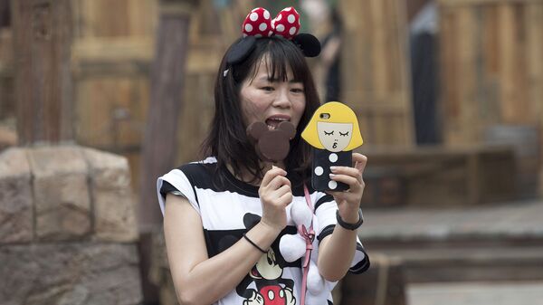 Посетительница первого на территории континентального Китая парка развлечений Диснейленд в Шанхае ест мороженое в виде Микки Мауса