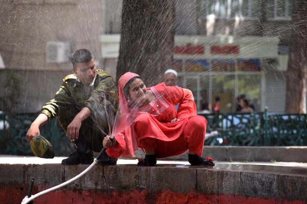 Жители Душанбе спасаются от жары возле фонтанов